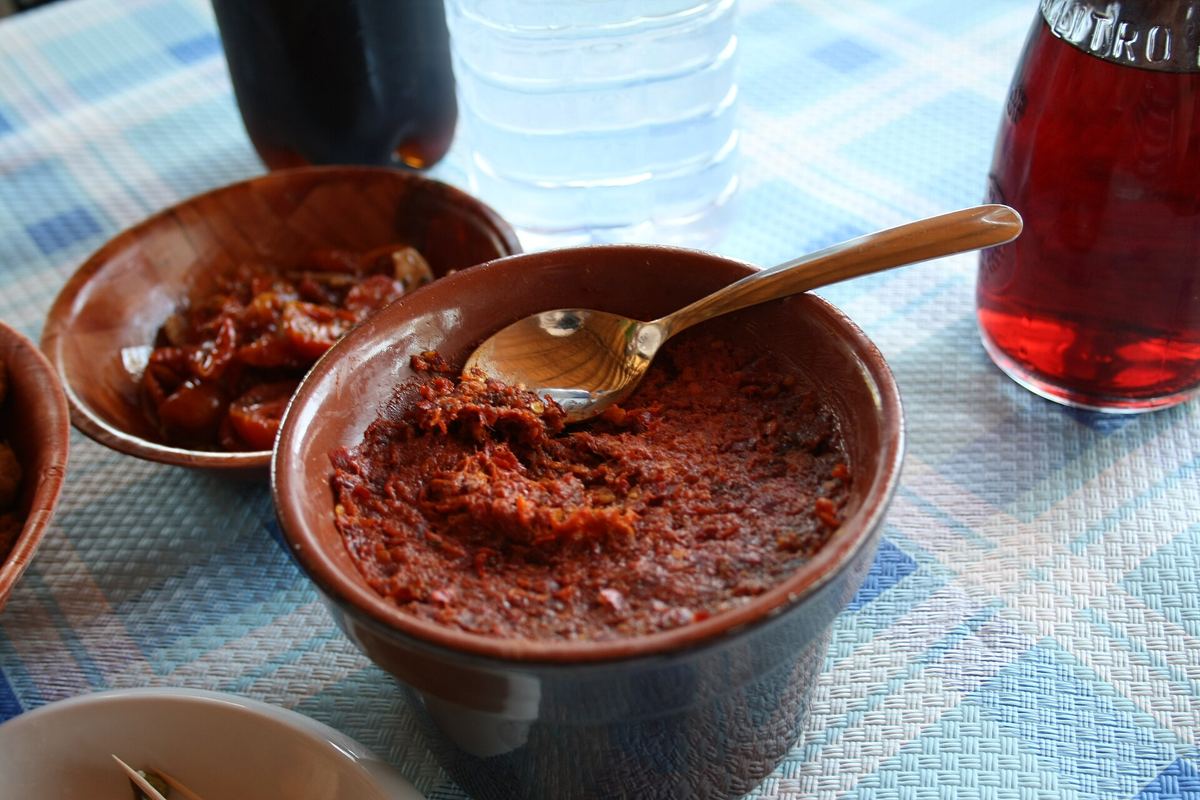 'Nduja in ciotole di terracotta con un cucchiaino, su una tovaglia a quadri